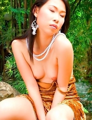 Olive Moon sits outside and she has her gold dress on. She has a necklace that hangs on her neck.